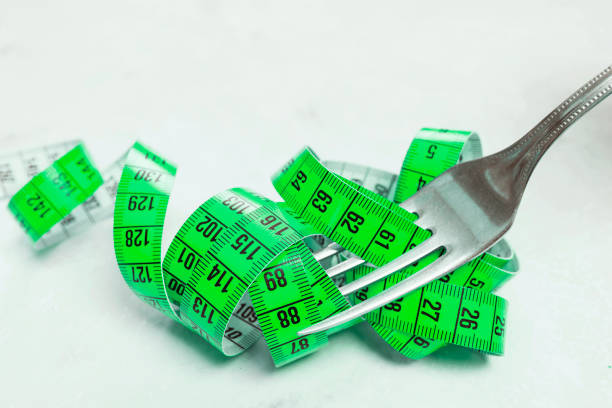 istock The measuring tape is green, wrapped around a plug lying on a white surface. 911115548