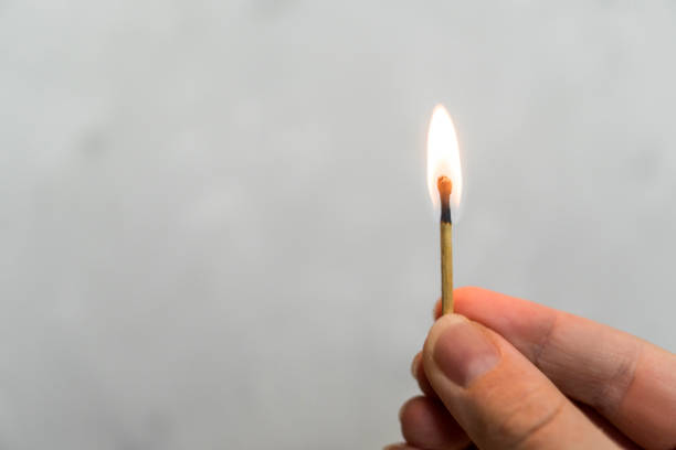 istock Hand burning match stick. A photo on a gray background. 911115910