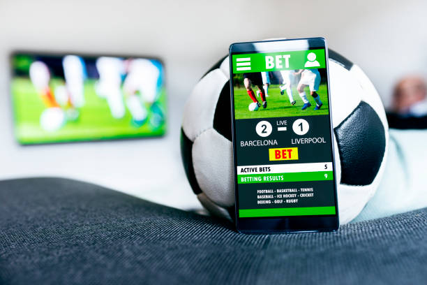 istock Soccer ball and mobile phone with betting app side by side 911119322
