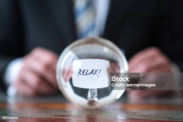 Man Holding Paper With The Word Relax In Front Of Glass Ball Stock Photo - Download Image Now