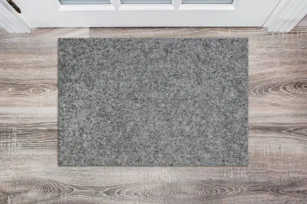 Blank grey woolen doormat before the white door in the hall. Mat on wooden floor, product Mockup.