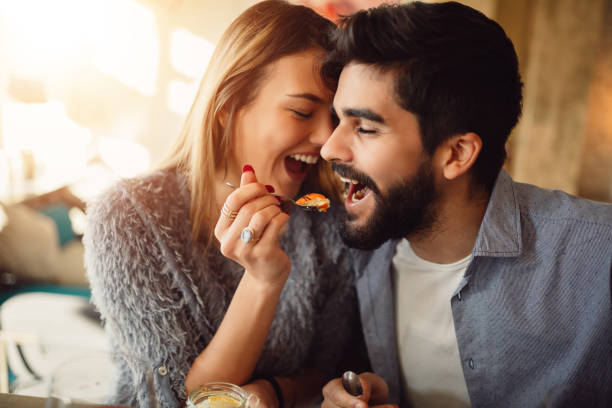 Close-up of a romantic young couple while girl feeding her boyfriend. stock photo