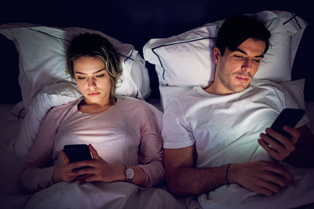 Mobile phone addiction - couple is texting and browsing in the bed Mobile phone addiction - couple is texting and browsing in the bed couple isolated wife husband stock pictures, royalty-free photos & images