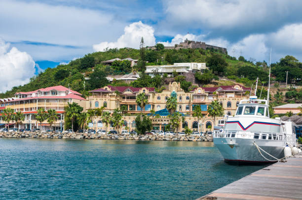Marigot Dock and Shops A small tour boat docks at the pier of Marigot, Saint Martin to allow passengers to shop at the nearby open air markets or the upscale shops that face the shore. saint martin caribbean stock pictures, royalty-free photos & images