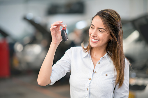 Woman taking her car to the garage and holding her keys while smiling