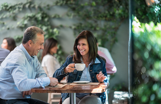 Portrait of a happy adult couple having a cup of coffee at a cafe and laughing - lifestyleÂ
