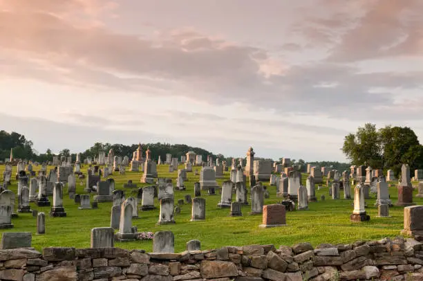 rural graveyard filled with old grave stones set on picturesque hill behind fieldstone wall