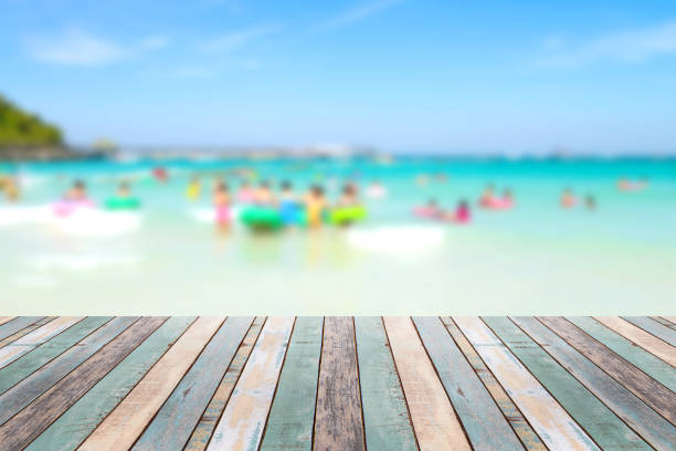 istock Wood table top with blurred people at the beach 911263116