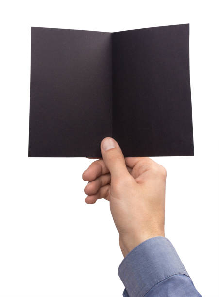 istock Mockup A6 empty blank black postcard horizontally bent in half holds the man in his hand in shirt. Isolated on a white background 911274436