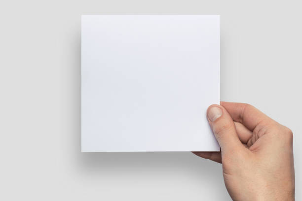 istock Mockup square empty blank white postcard holds the man in his hand. Isolated on a gray background 911274488