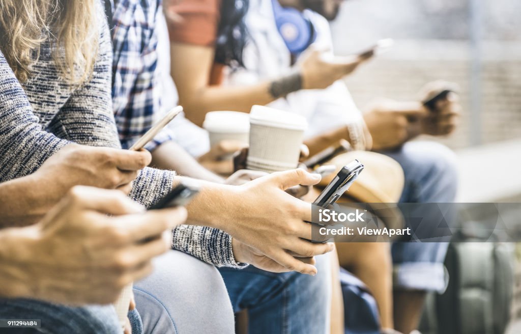 Multicultural friends group using smartphone with coffee at university college break - People hands addicted by mobile smart phone - Technology concept with connected trendy millennials - Filter image Social Media Stock Photo