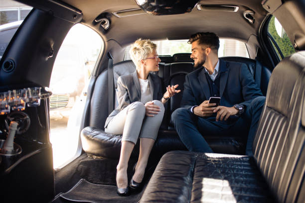 деловые люди, имеющие обсуждение в лимузине - luxury car women smart phone стоковые фото и изображения