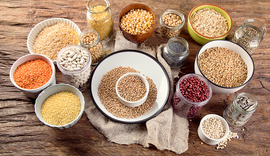 Ancient grains, seeds, beans on wooden background. Top view
