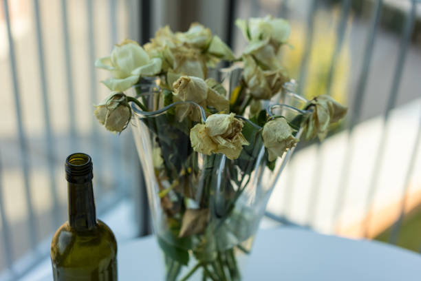 istock withered yellow roses and wine bottle 911313744