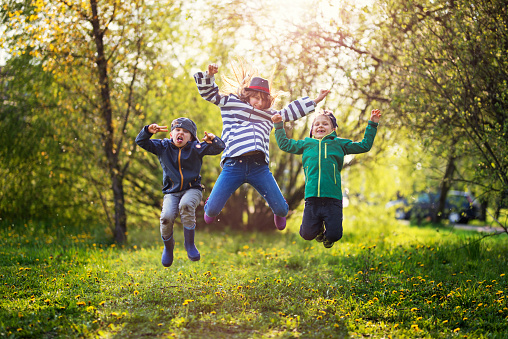 It's Spring! Finally the Spring has come! Three kids are feeling spring energy oveload. The are bustring with joy and fun on green grass and sunny spring day.\n