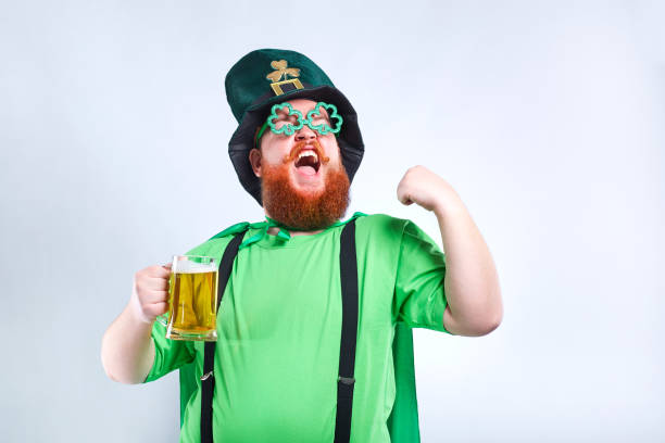 um homem gordo com uma barba no terno de st. patrick está sorrindo com uma m - santa hat fotos - fotografias e filmes do acervo