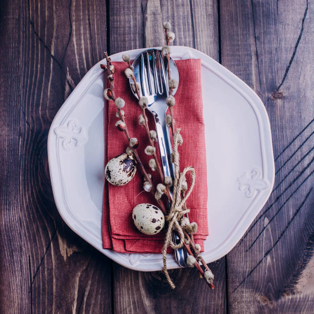 istock Easter table setting. White or beige plate, cutlery, eggs and pussy willow on wooden background table. Top view and copy space. 911322986