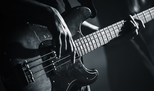 Electric bass guitar player hands, live music theme, black and white photo