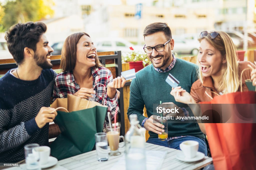 Grupo de cuatro amigos que se divierten un café juntos después de comprar - Foto de stock de Tarjeta de crédito libre de derechos