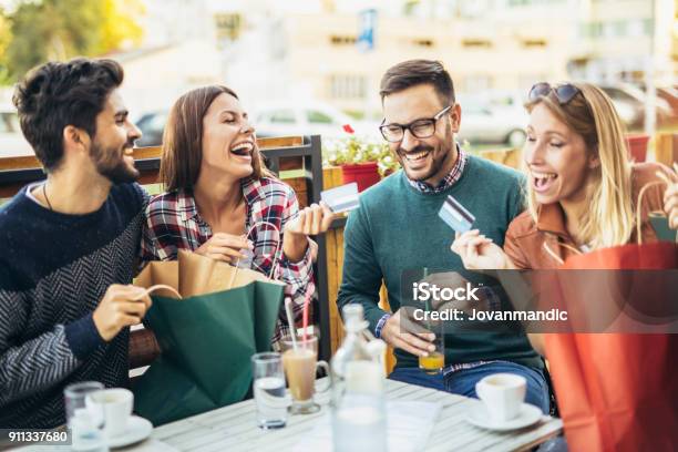 Grupo De Cuatro Amigos Que Se Divierten Un Café Juntos Después De Comprar Foto de stock y más banco de imágenes de Tarjeta de crédito