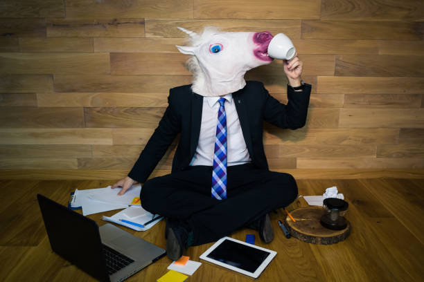 istock Young man wearing funny mask sits on the floor against a wall 911340366