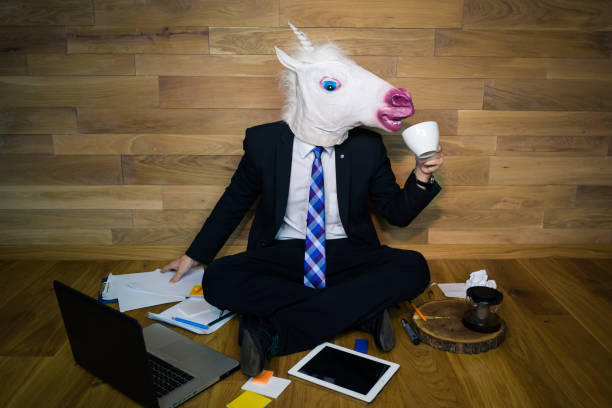 istock Young man wearing funny mask sits on the floor and drinks coffee 911340370