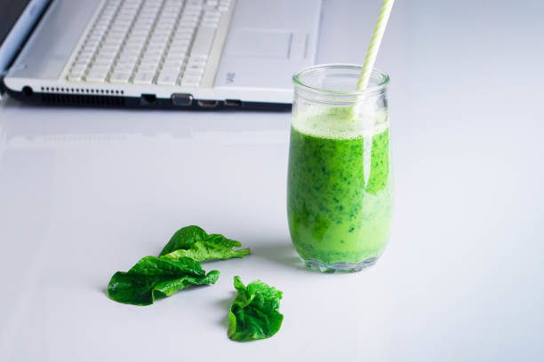 istock Healthy Drink Smoothie from Green Spinach and Apples in jar and computer on white table. Vegetarian and Diet Detox Drink Concept. Copy space, horizontal image 911344074