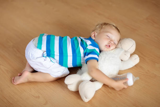 istock Baby sleeping on floor with toy and milk bottle. 911352420