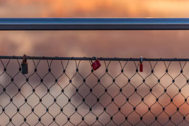 Lovelocks on a bridge railing with the light of the setting sun at the Rhein-Herne-Canal in Oberhausen, Germany in the background