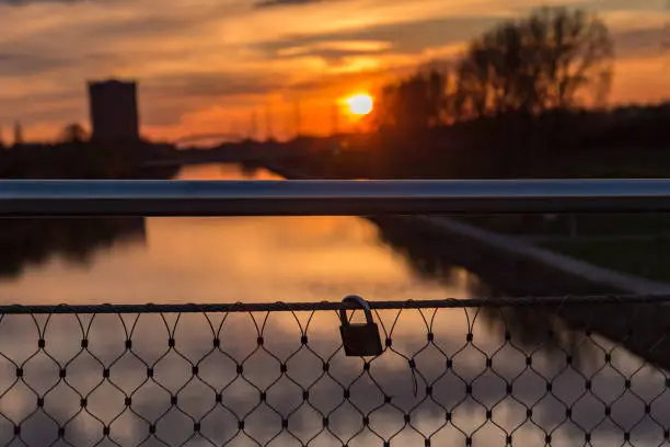 Lovelocks on a bridge railing with the light of the setting sun at the Rhein-Herne-Canal in Oberhausen, Germany in the background