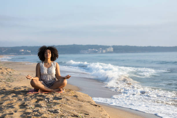 istock Africam woman sitting on sand and meditating 911366140