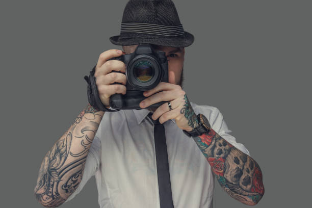 istock A man with tattooes on arms holding dslr photo camera. 911375604