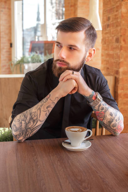 istock A man with tattooes on his arms in a cafe. 911378404