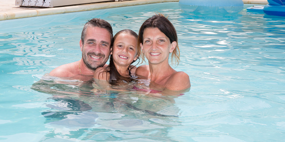 cheerful family in pool in summer