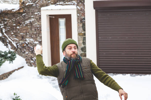 istock man with beard in his cap throws snowballs in yard 911397216