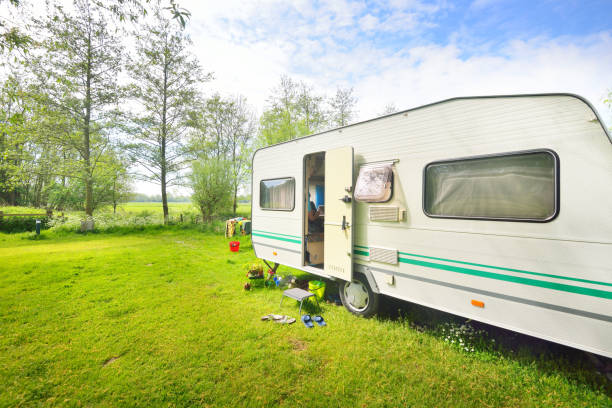 istock Caravan trailer camping on a green lawn under a tree in springtime 911397634