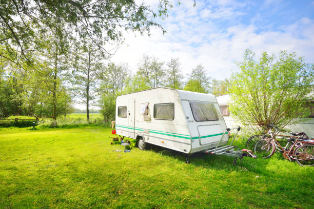 istock Caravan trailer camping on a green lawn under a tree in springtime 911397654