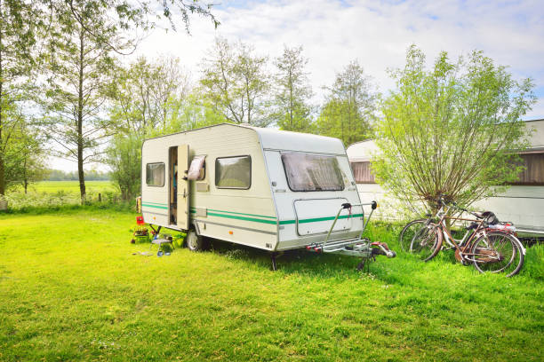istock Caravan trailer camping on a green lawn under a tree in springtime 911397660