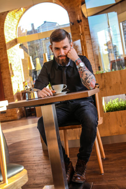 istock Male with tattoo on arms in a cafe 911399136