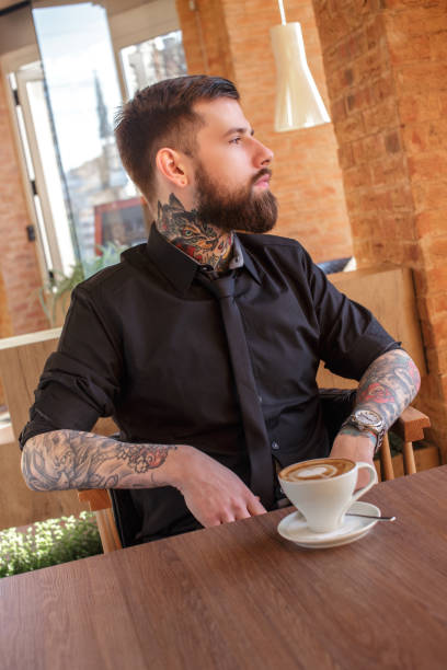 istock A man with tattooes on his arms in a cafe. 911404122