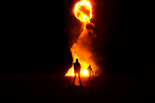 Silouette of firemen infront of big fire with fireball