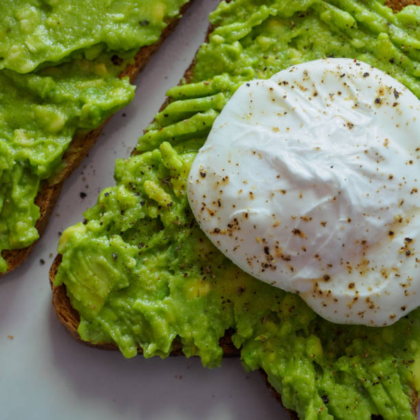 Poached egg on a smashed avocado toast with ground black pepper.