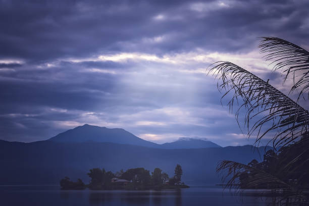 Small home on the tiny island in the middle of the stunning Lake Maninjao at sunset, Sumatra Island, Indonesia