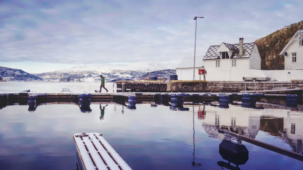 Man alone on a dock by the sea, at Herand, Hordaland, Bergen, Norway