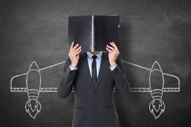 istock Businessman holding diary in front of his face 911429412