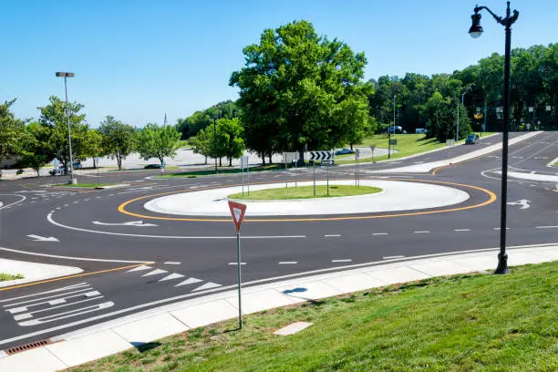 Horizontal shot of a traffic roundabout intersection under a blue sky.