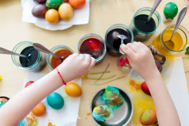 Young girl painting Easter eggs by the table