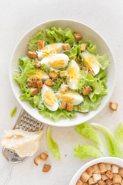 istock Caesar salad with eggs, lettuce and parmesan cheese on plate. Top view 911478038