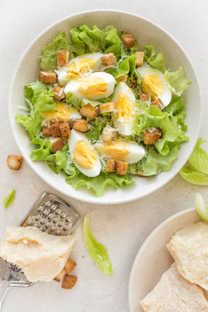 istock Caesar salad with eggs, lettuce and parmesan cheese on plate. Top view 911478106