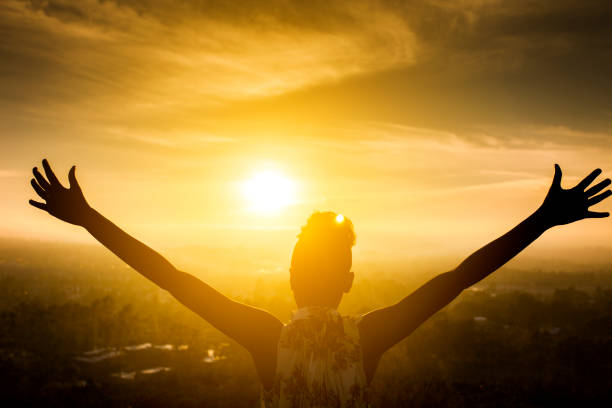 Black Girl Raising Arms over Valley in Sunset Silhouette of a beautiful black girl raising her arms over the valley as the sun sets punching the air stock pictures, royalty-free photos & images